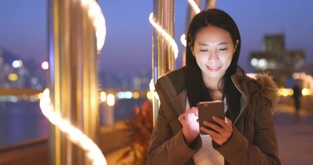 Poster - Chinese woman use of mobile phone in the winter time, woman wearing winter jacket at night