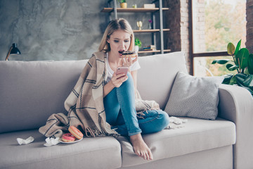 I don't love you anymore! Concept of problems in relationship. Disappointed young woman is eating tasty sugary donuts and looking old photos on her cellphone