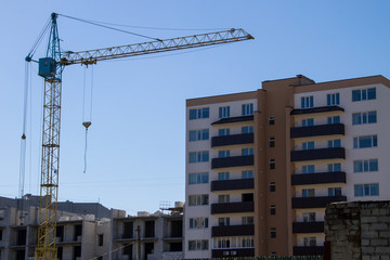 Building crane and building under construction against blue sky