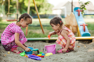 Two girls play in the sandbox 