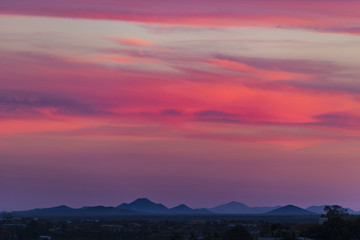 super pink horizontal clouds light up over a small town in the southwest