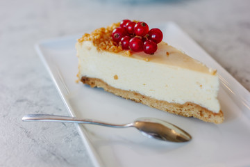 Wall Mural - Cheesecake with red currant berries on white plate.