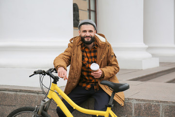 Poster - Attractive young hipster with cup of coffee and bicycle on city street