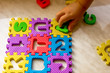 Colorful foam puzzle letters and numbers in kid's hands on a light table
