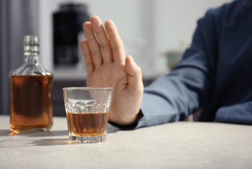 Man rejecting glass of alcohol indoors