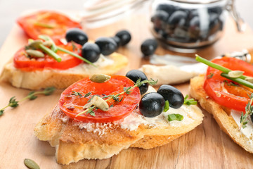 Wall Mural - Tasty bruschetta with tomato and olives on wooden board, closeup