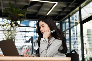 woman holding a credit card and using laptop computer for online shopping at cafe. businesswoman purchase goods from internet at office. female adult make payment on bank website at workplace