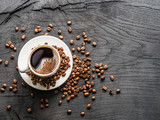 Fototapeta Kawa jest smaczna - Cup of coffee surrounded by coffee beans. Top view.