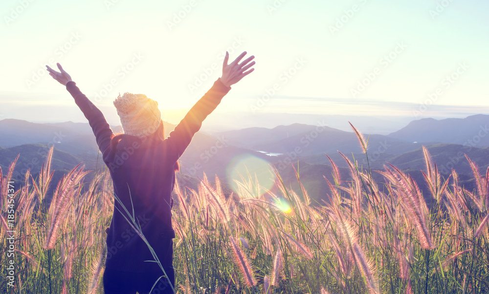 Happy Woman Enjoying Nature on grass meadow on top of mountain cliff with sunset outdoor. Freedom concept. - obrazy, fototapety, plakaty 
