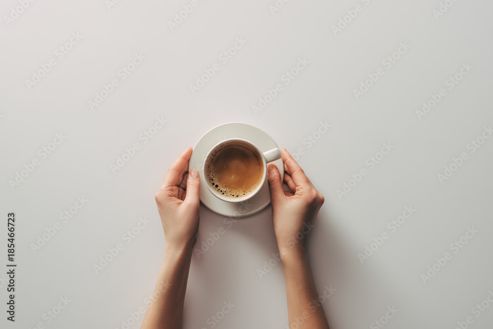 Obraz na płótnie top view of female hands and cup of coffee with saucer on grey w salonie