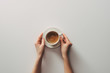 © LIGHTFIELD STUDIOS - top view of female hands and cup of coffee with saucer on grey