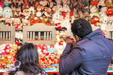 Back view of tourists playing shooting game to win plush toys on the wall at Christmas funfair winter wonderland in London
