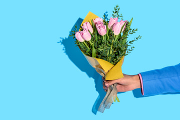 partial view of african american man holding bouquet of flowers on blue background