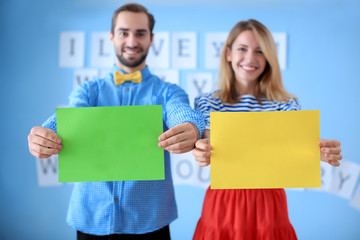 Wall Mural - Happy couple holding color papers indoors