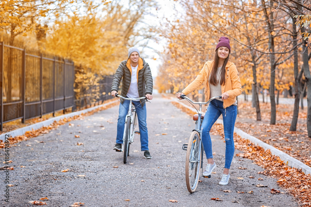 Young couple riding bicycles in park