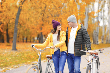 Poster - Young couple walking with bicycles in park