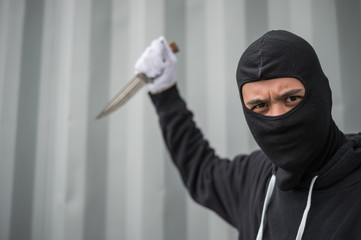 portrait of criminal or bandit wear black mask holding a knife and looking to camera, concept of cutthroat and assassin