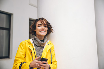 Wall Mural - Smiling young woman chatting by mobile phone. Looking camera.