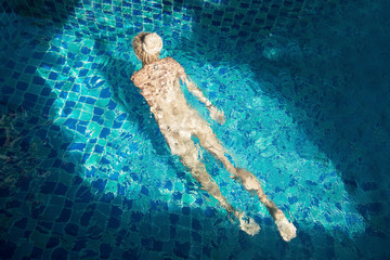 Female with dread locks swimming in swim pool at summer day outdoor