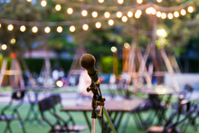 Microphone Stand For The Singer With The Light Hanging And Table Set For Party In The Park Background