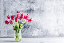 Bouquet Of Pink Tulips In A Glass Vase  On Grey Background.