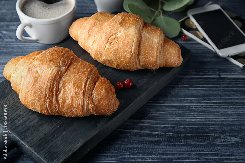 Composition with yummy fresh croissants and mobile phone on wooden table