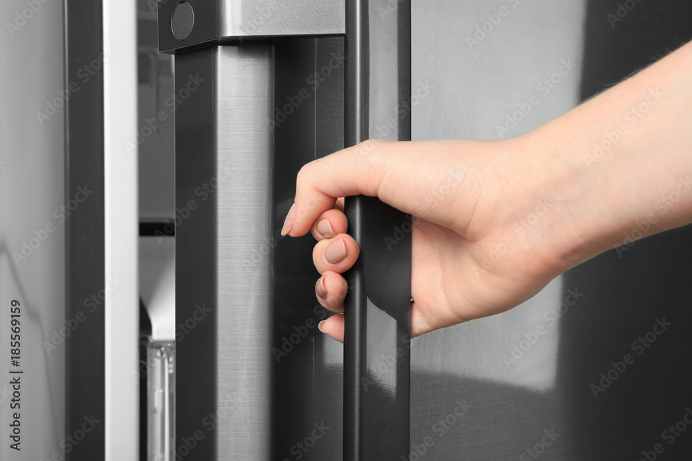 Woman opening refrigerator door, closeup