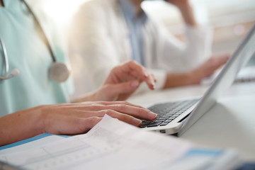 Closeup of nurse's hands typing on laptop keyboard