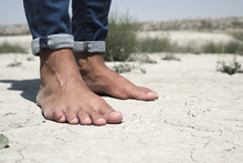 Bare Feet Of A Man On A Cracked Dry Soil