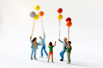 Miniature people children holding balloon  with sunlight, happy family day concept.