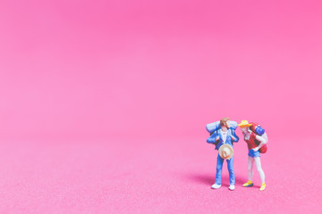 Miniature people : Couple of travellers on pink background , Valentine's day concept