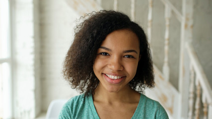 Wall Mural - Closeup portrait of beautiful african american girl laughing and looking into camera at home