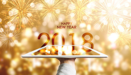 Happy New Year 2018, Hand holding digital tablet with luxury gold Bokeh fireworks background