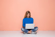 © stacestock - Serious woman working with laptop while sitting on floor isolated. Woman typing on laptop computer while sitting on the floor with legs crossed.