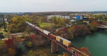 AUSTIN, TX - Circa December, 2017 - A Slow Forward Aerial View Of A Cargo Train Traveling Over A Bridge Over The Colorado River In Downtown Austin, Texas.  	