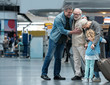 © Yakobchuk Olena - Happies moment. Full length of aged father is hugging his adult sun and expressing gladness. Old joyful woman is embracing her little grandchild while standing in waiting hall at airport. Copy space