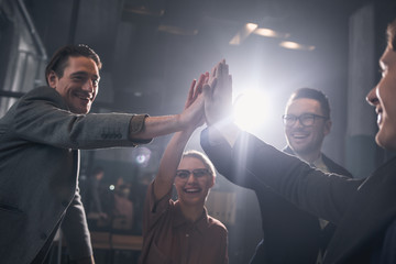 Aufkleber - Low angle happy woman and glad males rising hands into pyramid while situating in room. Career and achievement concept