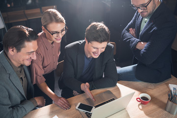 Aufkleber - Top view cheerful males and happy woman watching at monitor of digital device while locating at table. Startup concept