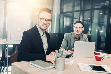 Aufkleber - Portrait of smiling unshaven male working with serene affiliate while locating at table in office. Occupation and conversation concept