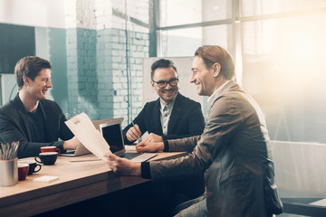 Aufkleber - Outgoing male discussing information while holding document in hands. They sitting at table in apartment. Conversation and labor concept