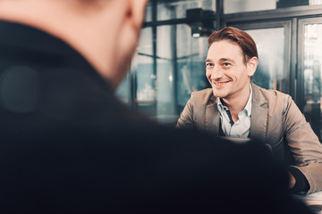Aufkleber - Portrait of cheerful businessman telling with partner while locating at desk. Affiliate turning back to camera. Conversation and work concept