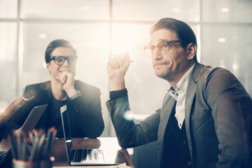 Aufkleber - Portrait of orderly male grimacing and rising arm up while situating near laughing comrade at desk in office. Career concept