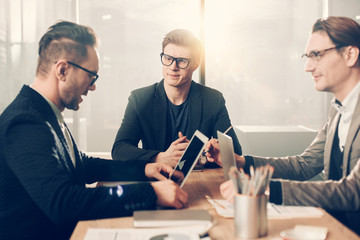 Aufkleber - Portrait of serene man speaking with partners while locating at table near them. Serious affiliate looking at screen of laptop. Occupation concept