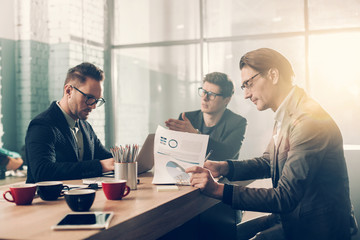 Aufkleber - Serious businessman sitting at table while signing documents. Serene partner typing in laptop. Job concept