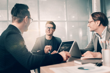 Aufkleber - Cheerful young partners telling with each other while locating at desk in office. Career concept