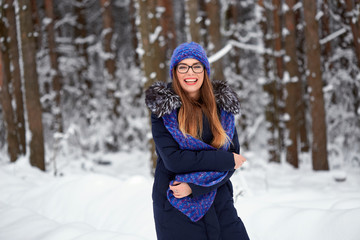 Wall Mural - girl in blue knitted scarf with hat in winter forest.