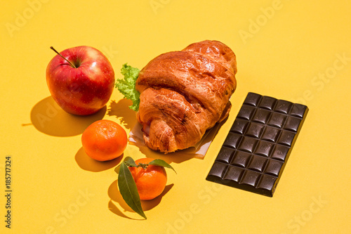 Fotografie, Tablou The apple, chocolate and croissants on yellow background