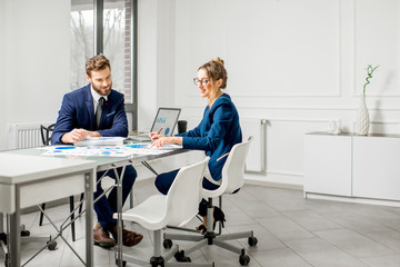 Marketer or analityc manager team dressed in suits working with paper charts and laptops at the white office interior