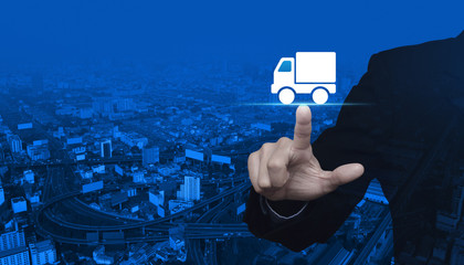 Businessman pressing truck delivery icon over modern city tower, street and expressway, Business transportation service concept