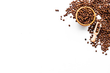 Fresh roasted coffee beans in bowl and scoop on white table top view copyspace. Coffee background.